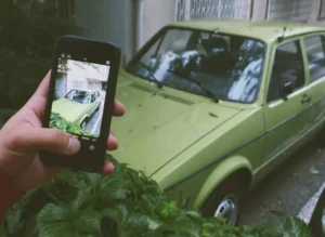 A Person Taking a Photo of a Green Car