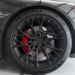 Detailed view of a stylish car wheel with red brake caliper in a modern garage setting.